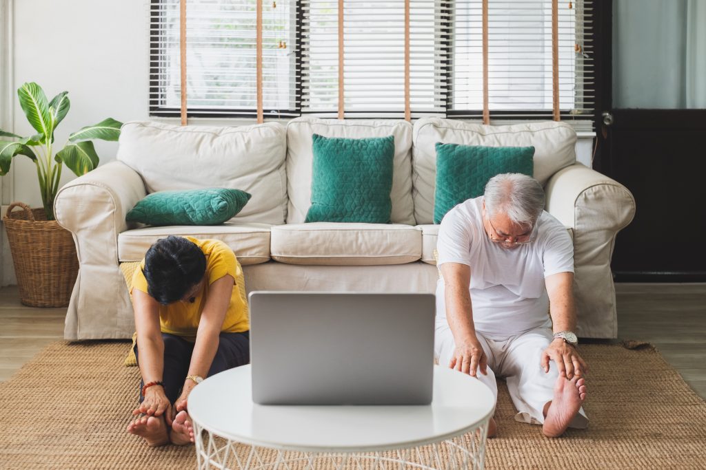 Lady and man exercising on the floor in front of a computer screen